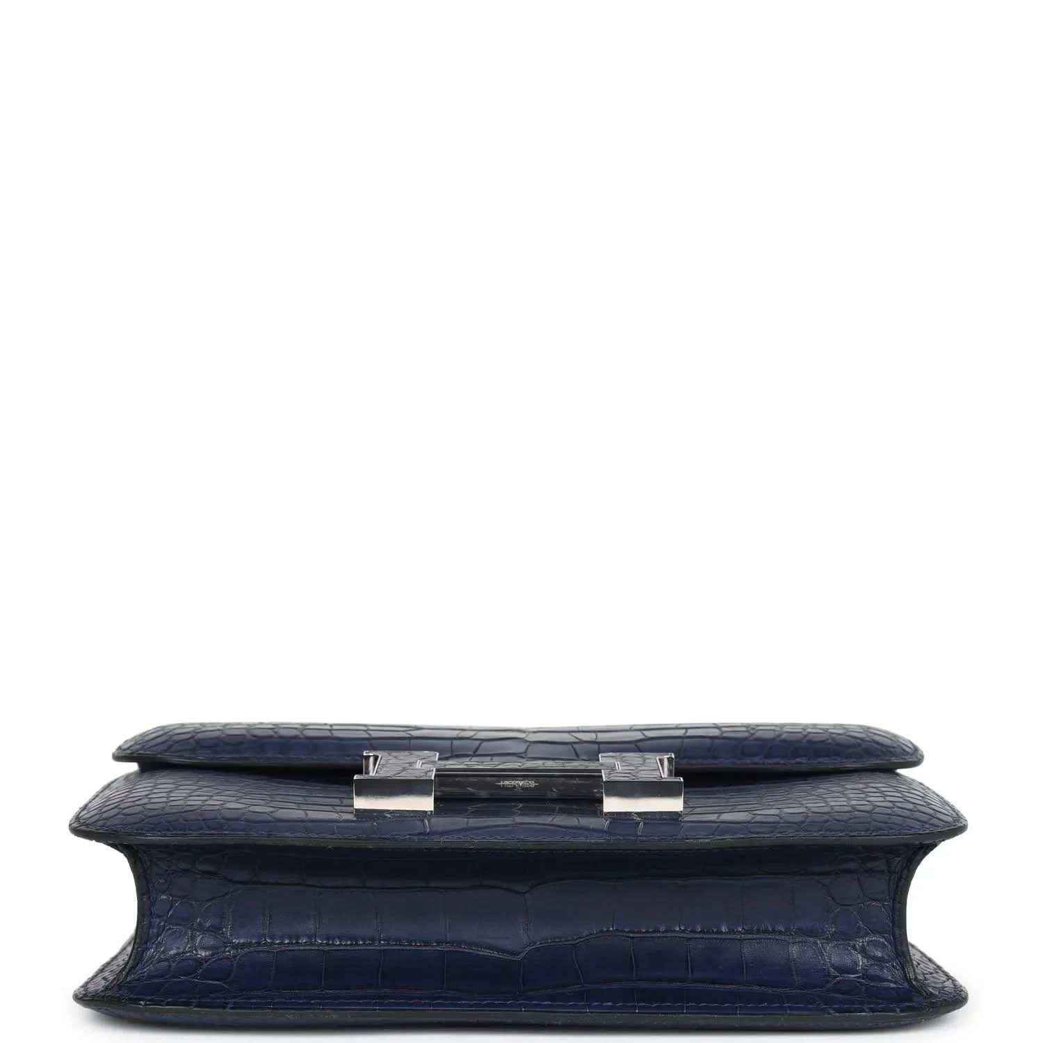 Blue alligator-effect handbag underside with side tab hardware and flat base