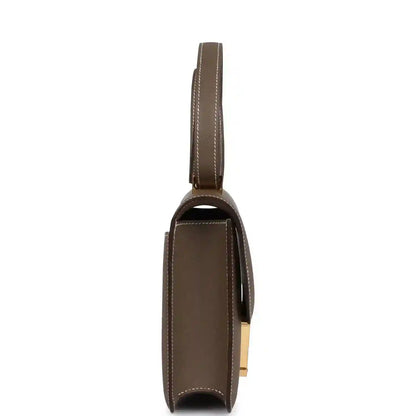 Taupe leather shoulder bag side view with slim strap and gold hardware detail