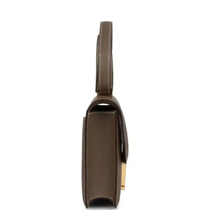 Taupe leather shoulder bag side view with slim strap and gold hardware detail