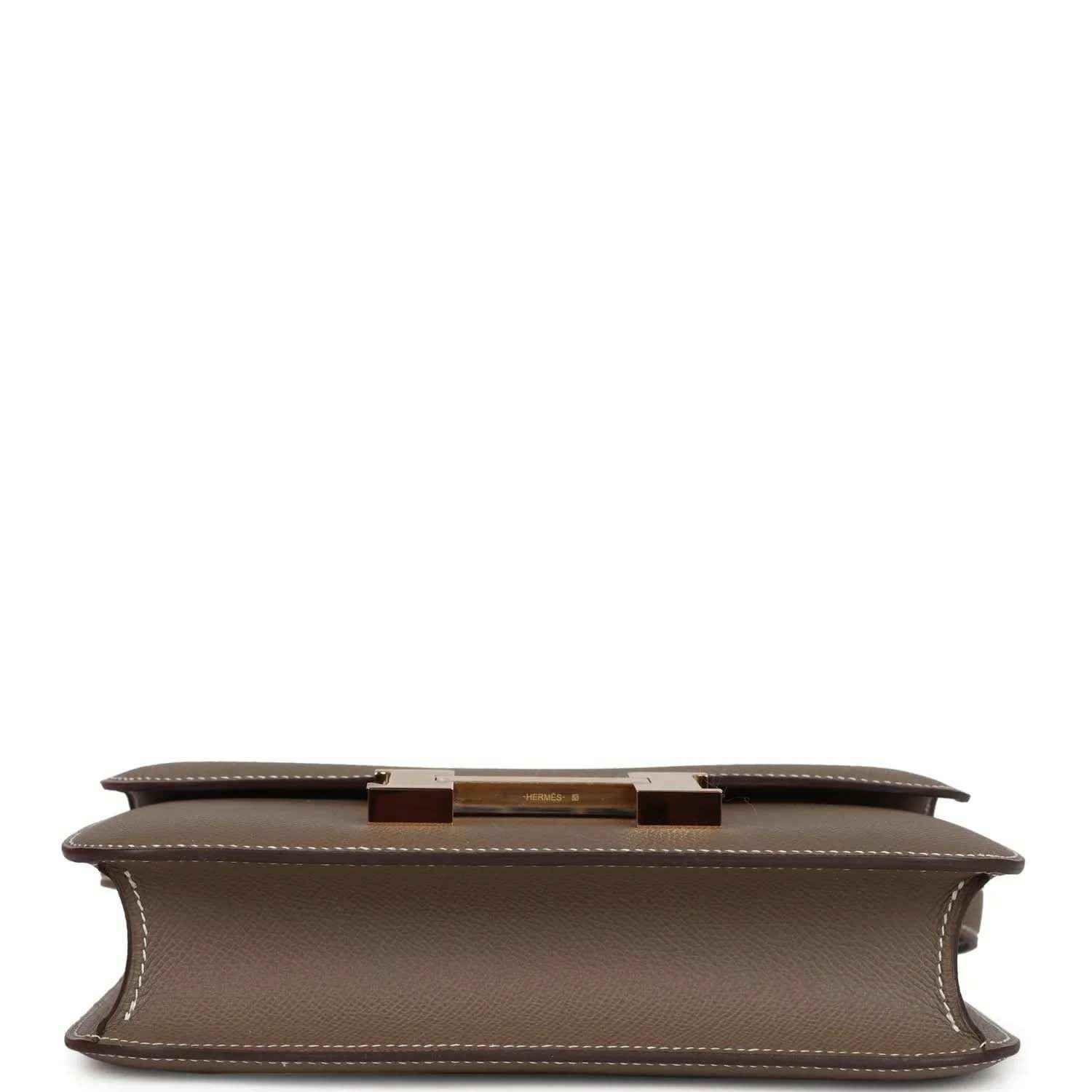 Taupe leather bag underside with center hardware bar and stitched edges