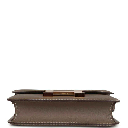 Taupe leather bag underside with center hardware bar and stitched edges