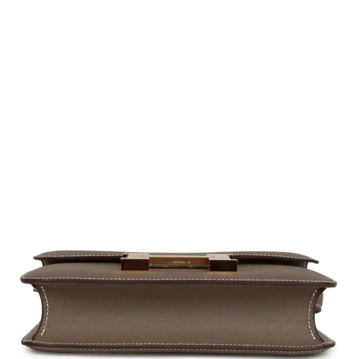 Taupe leather bag underside with center hardware bar and stitched edges