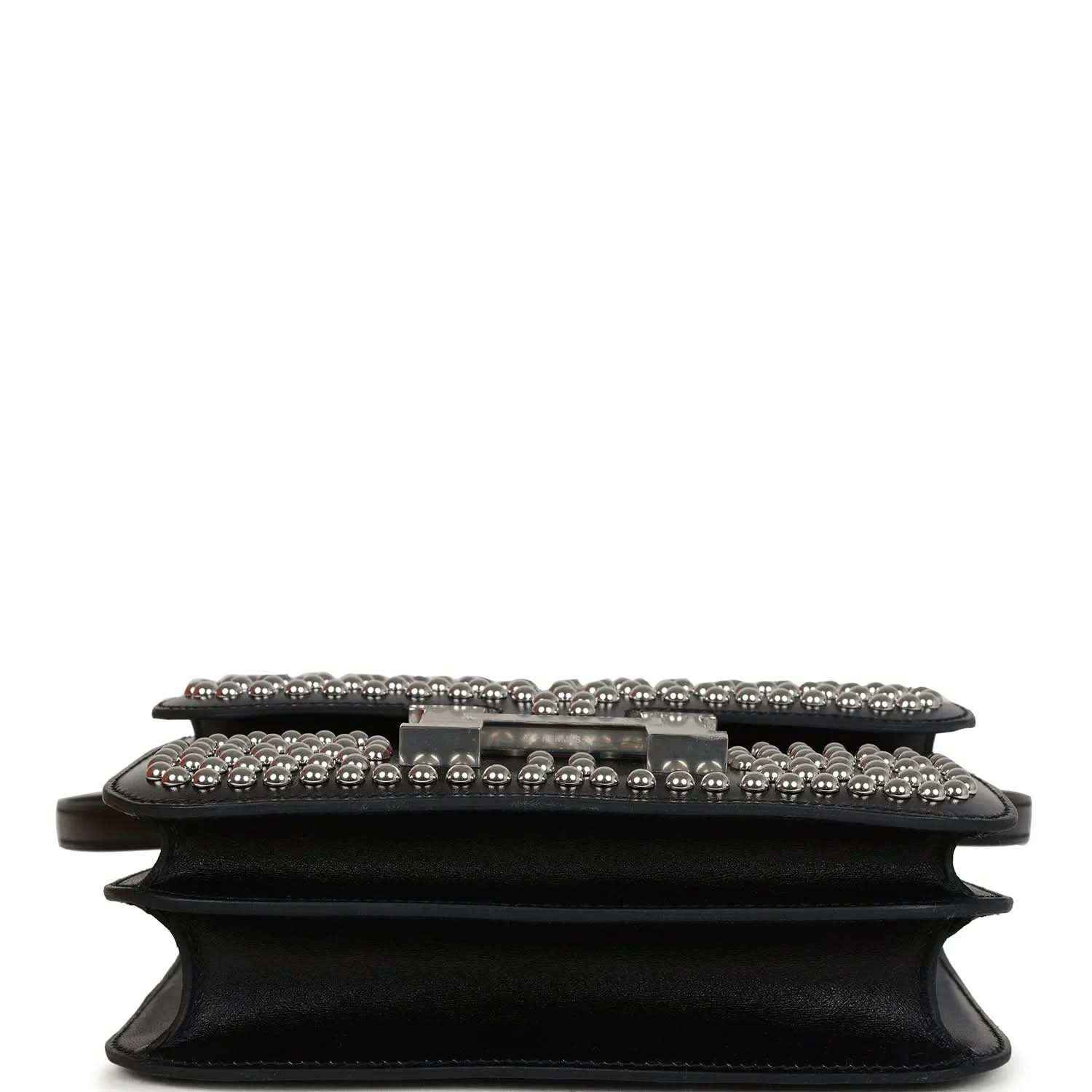Black leather bag close-up of front flap, studded trim and riveted edge