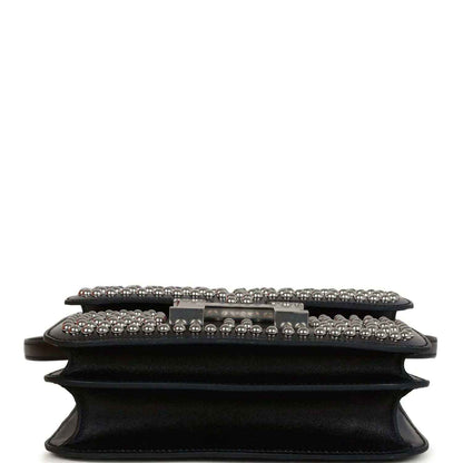 Black leather bag close-up of front flap, studded trim and riveted edge
