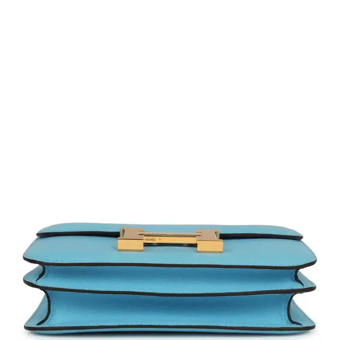 Mini crossbody bag in light blue leather shown from underside with gold hardware bar