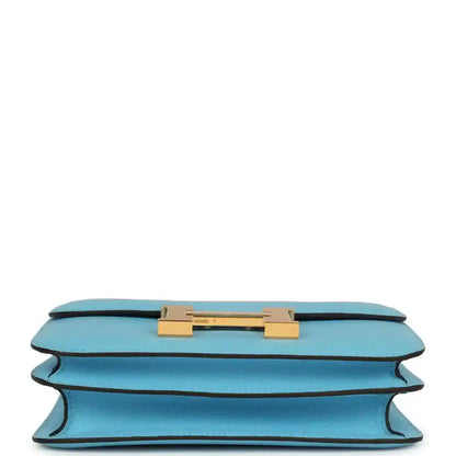 Mini crossbody bag in light blue leather shown from underside with gold hardware bar