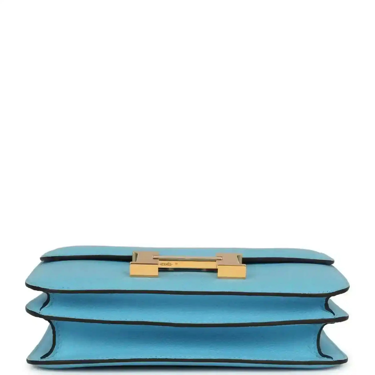 Mini crossbody bag in light blue leather shown from underside with gold hardware bar