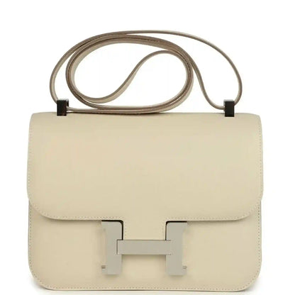 Beige leather crossbody handbag with flap and turn-lock clasp, top handle strap