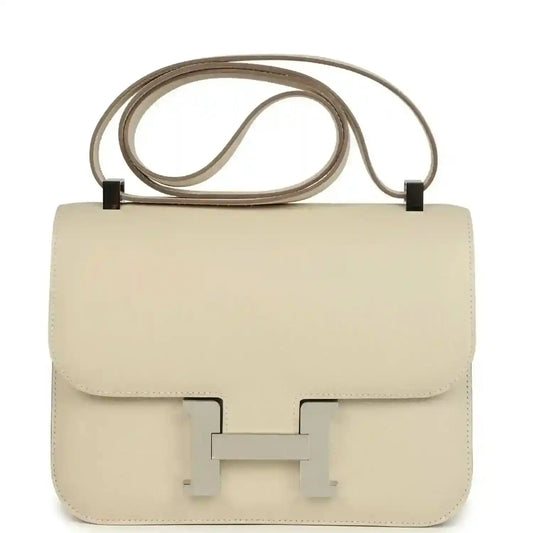 Beige leather crossbody handbag with flap and turn-lock clasp, top handle strap