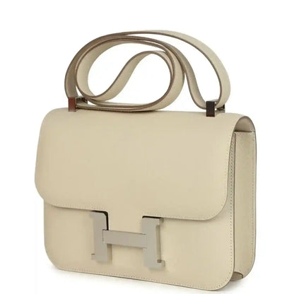 Beige leather handbag front and side view with flap and light silver turn-lock clasp