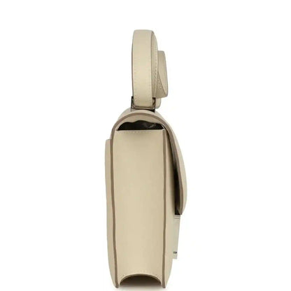 Beige leather handbag side view with top handle strap and flap closure hardware