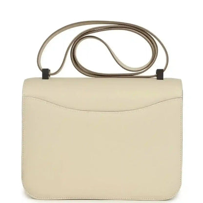 Beige leather handbag front view with curved flap and light silver clasp, top handle