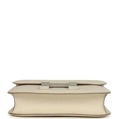 Beige leather handbag base view with two light silver feet and flap hardware