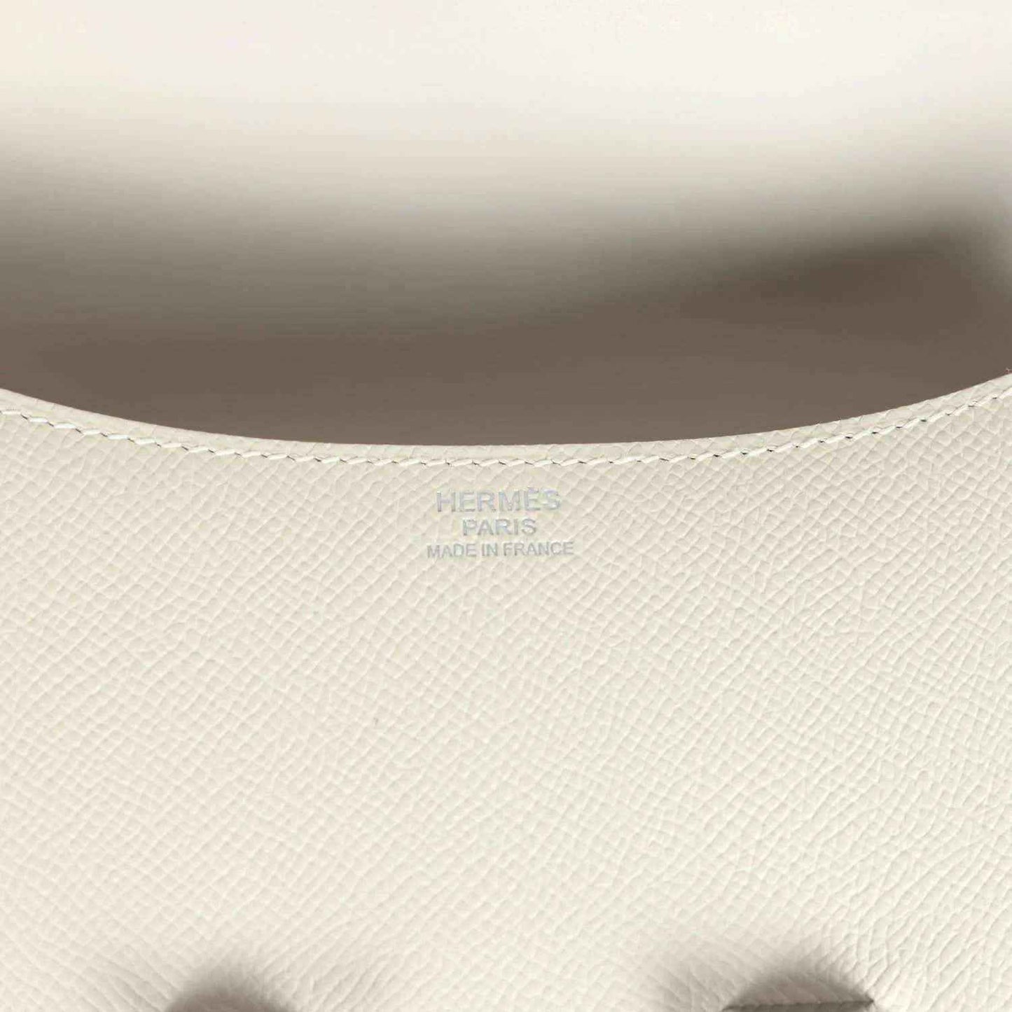 Close-up of beige textured leather handbag interior lining with embossed brand mark