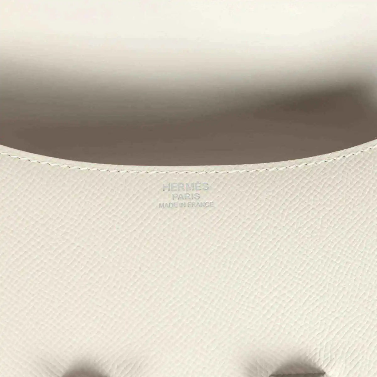 Close-up of beige textured leather handbag interior lining with embossed brand mark