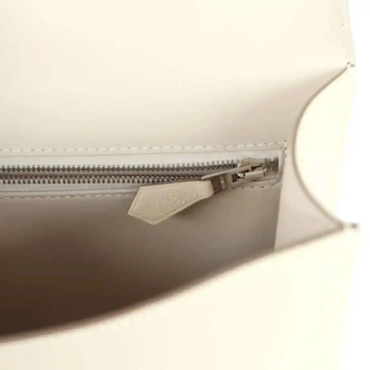 Beige leather handbag interior with zipper pocket and metal zipper pull