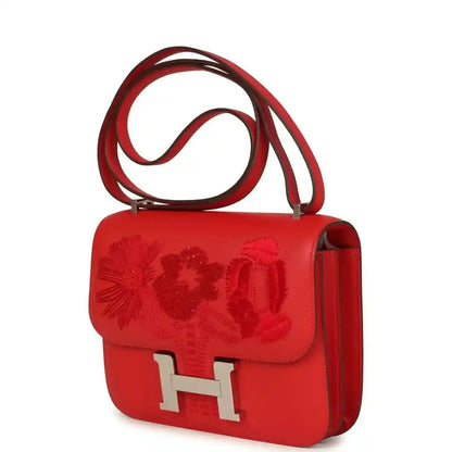 Red leather shoulder bag with embossed floral flap and silver H clasp, side profile