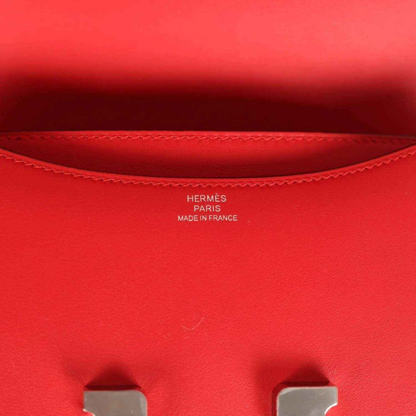 Red leather bag interior lining with stitched edge and small brand stamping