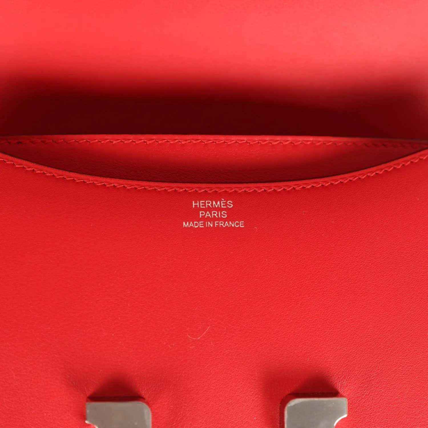 Red leather bag interior lining with stitched edge and small brand stamping