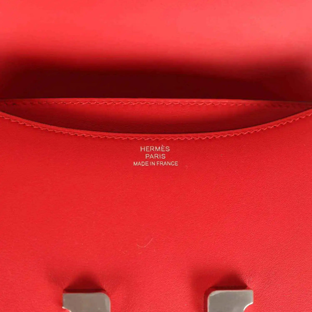 Red leather bag interior lining with stitched edge and small brand stamping
