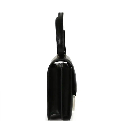 Black calfskin bag side view with top handle and H clasp hardware.