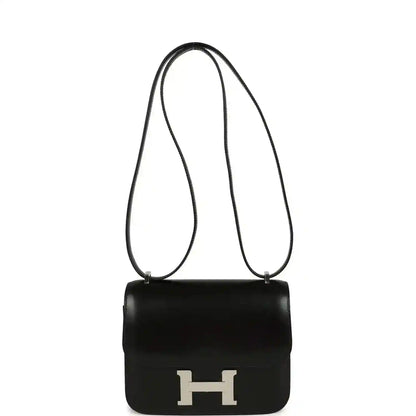 Black calfskin crossbody bag with top handle, long strap, and front H clasp.