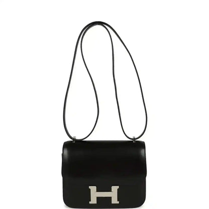 Black calfskin crossbody bag with top handle, long strap, and front H clasp.