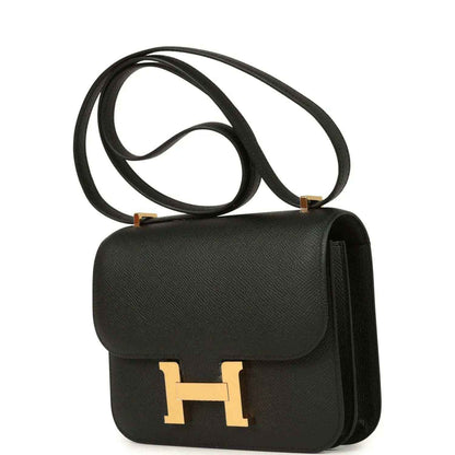 Black crossbody handbag with gold-tone H clasp and side pocket detail, textured leather.