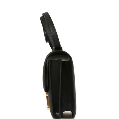 Black handbag back panel with gold-tone hardware detail and shoulder strap.