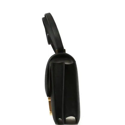 Black handbag back panel with gold-tone hardware detail and shoulder strap.