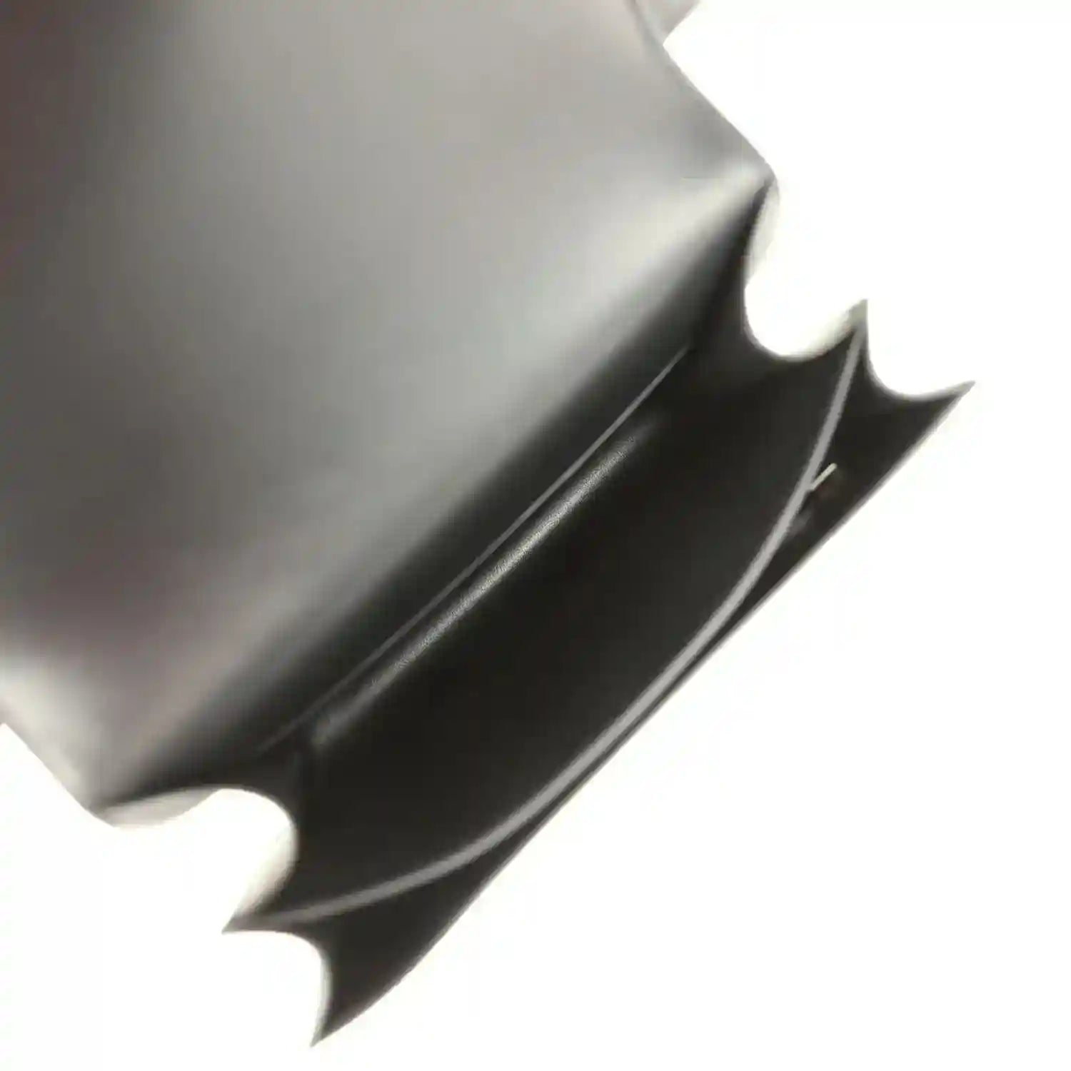 Black handbag interior with smooth lining and open top-flap edge.