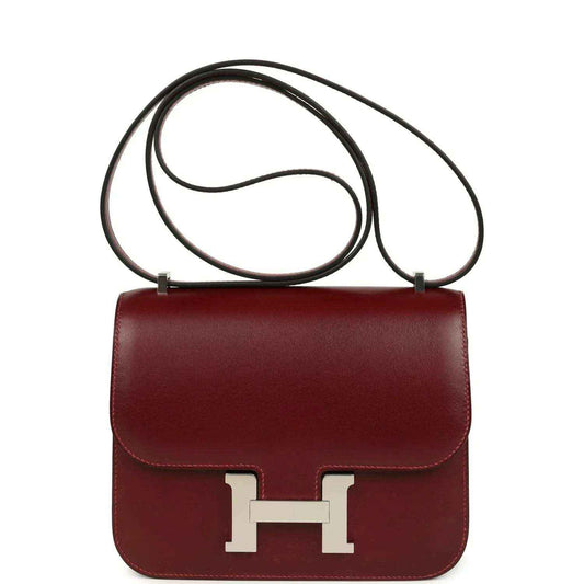 Burgundy leather crossbody bag with top handle and silver H clasp front.