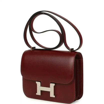 Burgundy leather flap crossbody bag with silver H clasp and long strap.