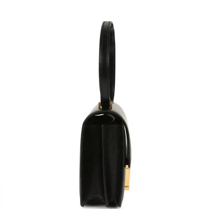 Black calfskin handbag with slim side profile and gold-tone hardware on strap
