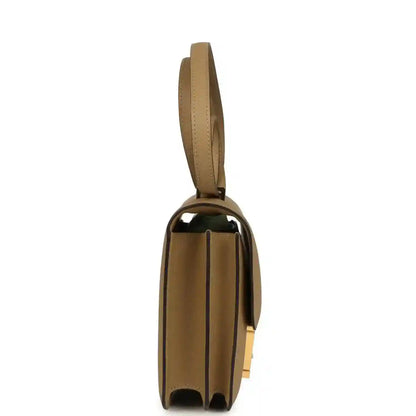 Tan leather crossbody bag with slim strap and gold-tone hardware, side profile