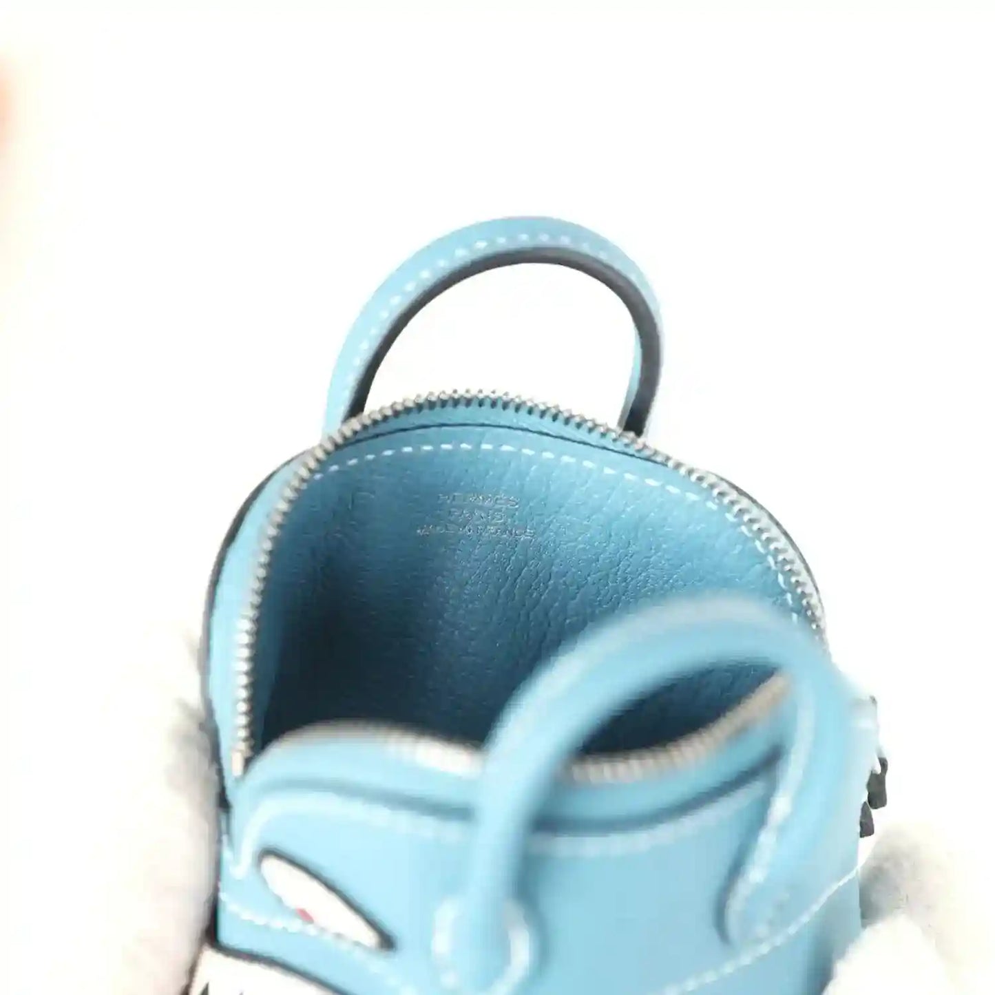 Hermes shark bag charm in blue leather, close-up of handle and front zipper edge