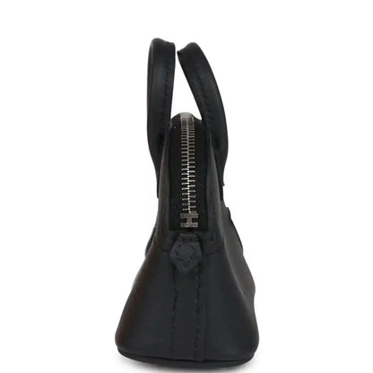 Black mini bag charm showing zipper track and stitched handle area