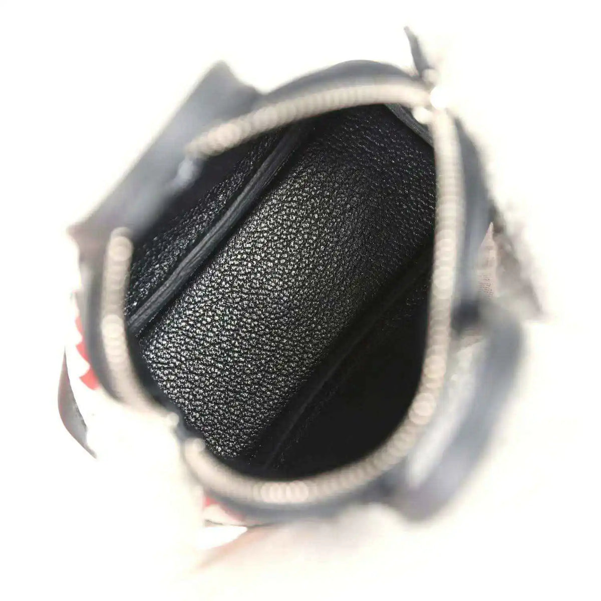 Black mini bag charm opening with textured interior lining and zipper area