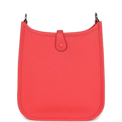 Red leather mini handbag with top handle and curved scalloped silhouette.