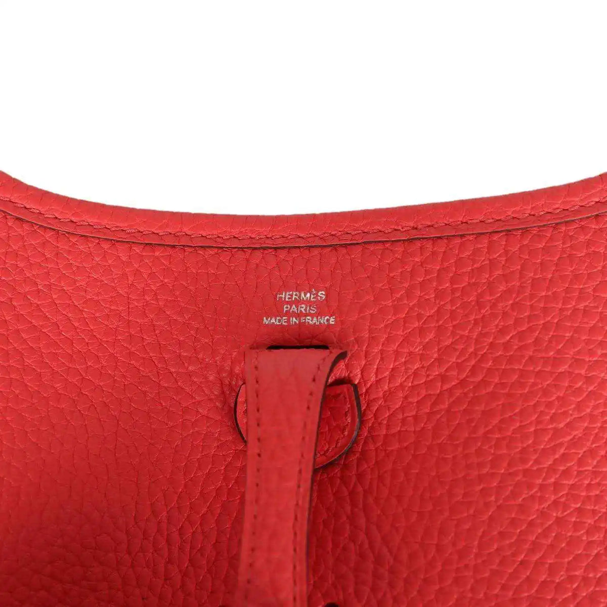 Red leather mini handbag interior stamp area with small leather tab detail.