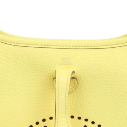 Close-up of lemon-yellow leather shoulder bag seam and stitched trim