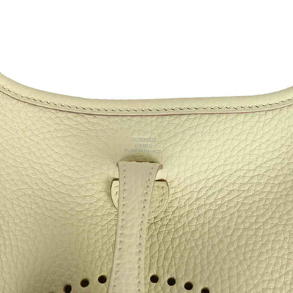 Light yellow leather mini crossbody bag close-up of top strap and stitching