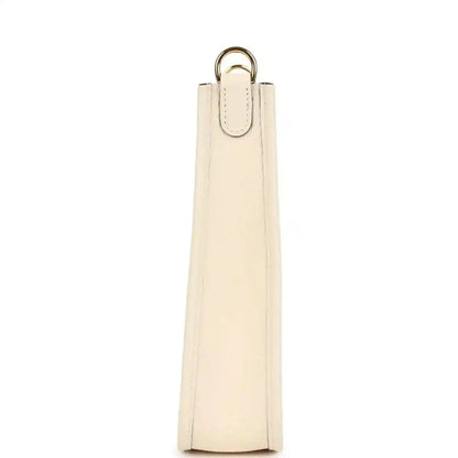 Light beige TPM bag strap hanging vertically with gold-tone top ring