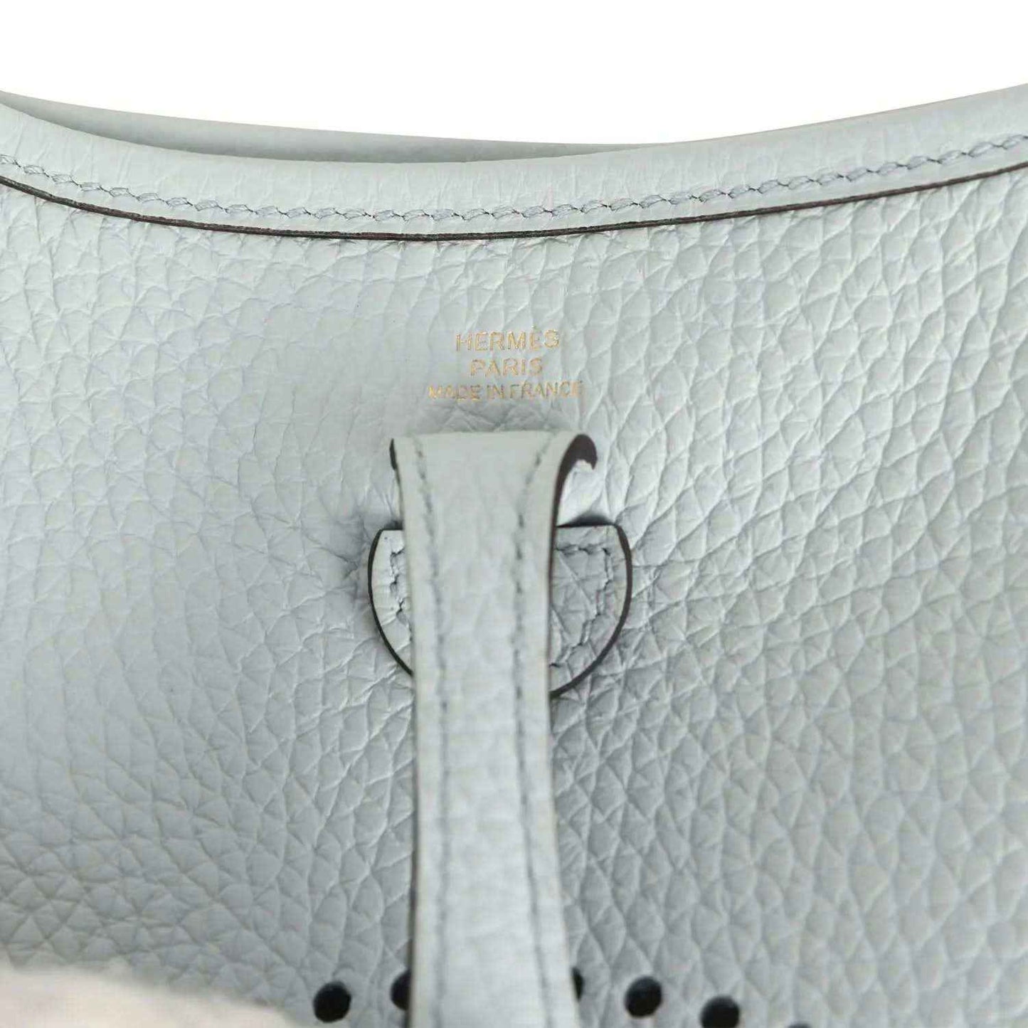 Evelyne TPM bag close-up: pale blue leather tab with printed marking and stitching