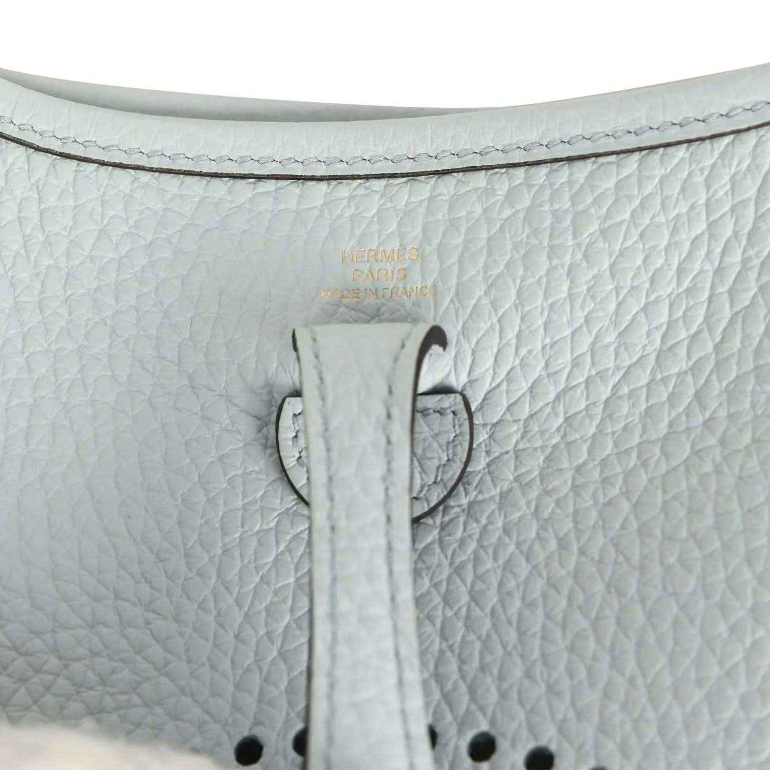 Evelyne TPM bag close-up: pale blue leather tab with printed marking and stitching