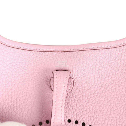 Mauve-pink leather crossbody bag close-up of strap fastening and perforated logo