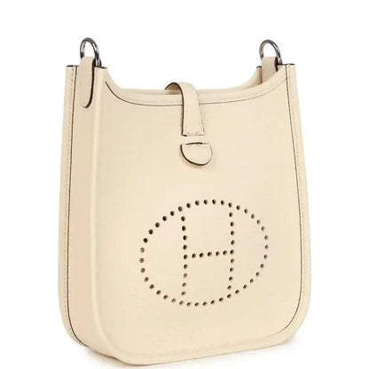 Cream textured leather hobo bag with top handle and perforated circular logo