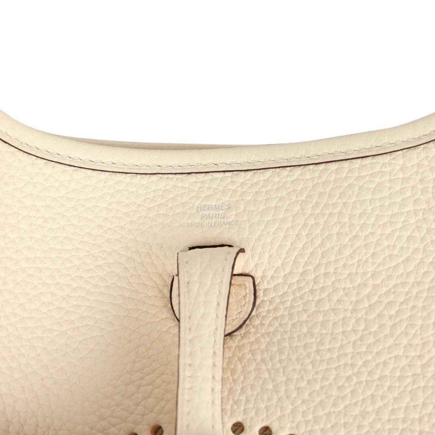 Close-up of cream leather bag strap tab with snap hardware