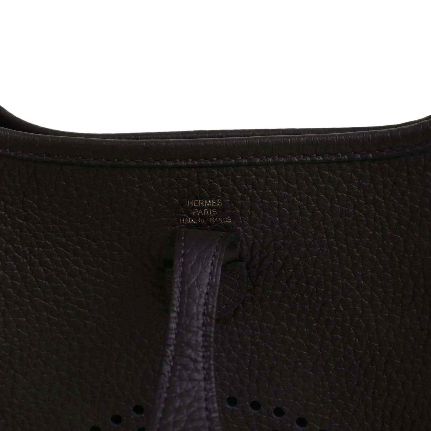 Black leather Evelyne TPM bag close-up of “Hermes Paris” stamp and vertical seam.