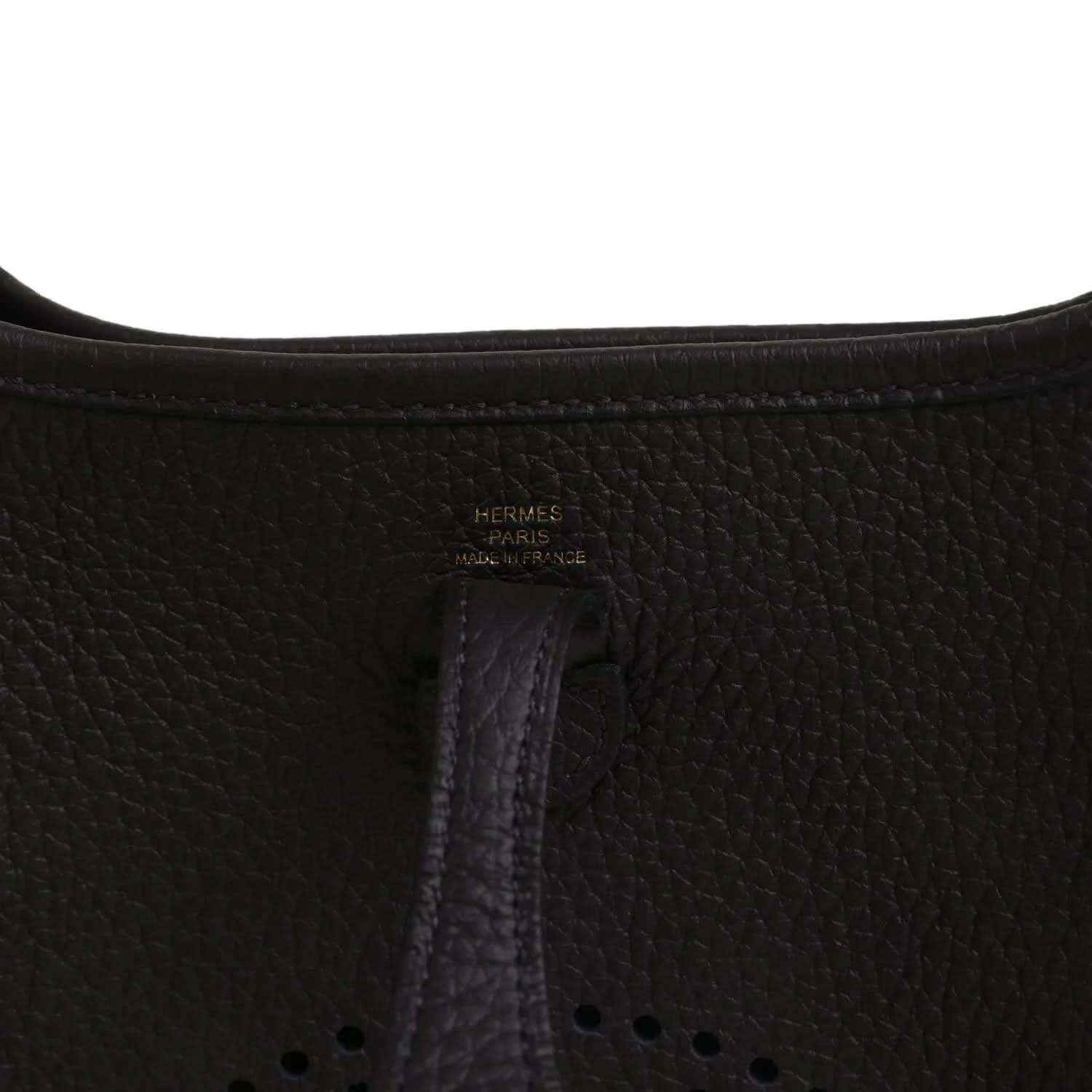 Black leather Evelyne TPM bag close-up of “Hermes Paris” stamp and vertical seam.